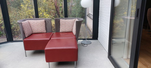 Deux fauteuils Montis Scene avec poufs. Rouges et anthracite, avec de jolis coussins.