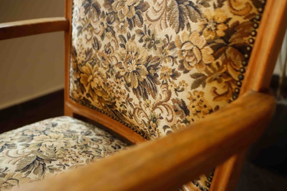Image 1 of Vintage salonfauteuil met bloemenpatroon op de bekleding en sierlijke armleuningen.