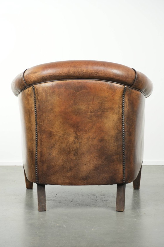 Image 1 of Schapenleren clubfauteuil met een mooie patina en een verfijnde afwerking met zwarte biezen
