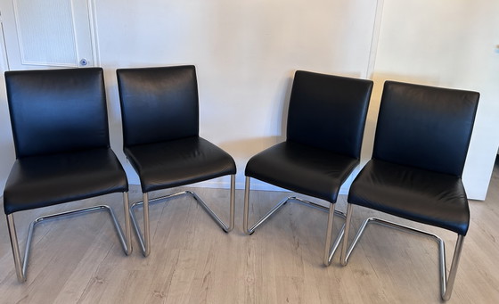 Image 1 of Ensemble de salle à manger Hülsta D2 – table à manger en verre avec 4 chaises en cuir noir à piètement luge