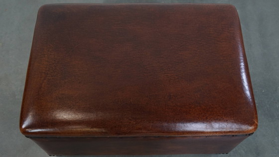 Image 1 of Cognac-kleurige schapenleren hocker met siernagels