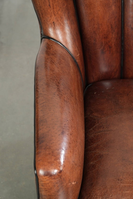 Fauteuil unique en peau de mouton aux couleurs chaudes et profondes, orné d'un passepoil noir. – Leather (photo 7 of 14)