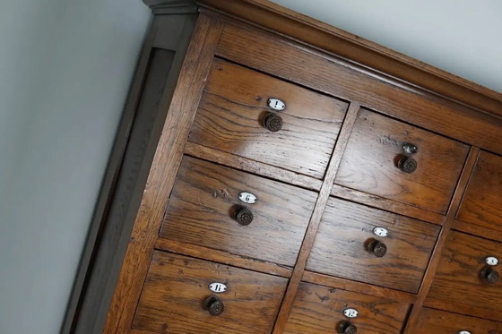 Image 1 of Grote Nederlandse eiken apothekerskast / kapperskast met emaillen schildjes, jaren 1900