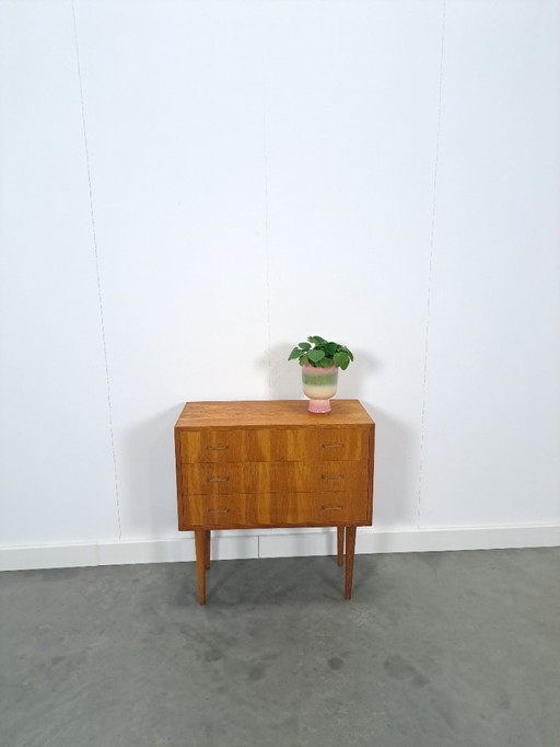 Cómoda danesa con patas altas y tiradores dorados.