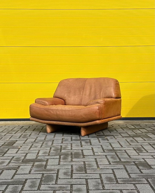 Sillón de salón vintage de piel color coñac.