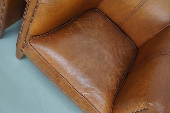 Image 1 of Dit paar cognackleurige leren clubfauteuils komt uit Nederland. Ze zijn bekleed met cognackleurig leer en zijn voorzien van meta