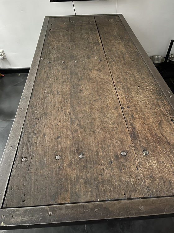 Image 1 of Industriele eettafel van oude werkbank met gietijzer onderstel y gelaste randen