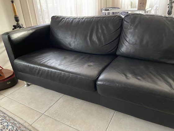 Image 1 of Black leather three-seater sofa.