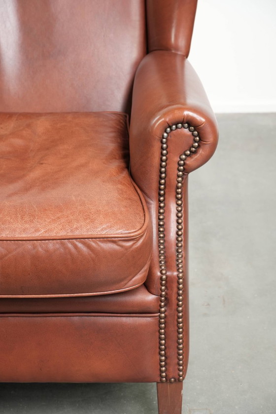 Image 1 of Comoda poltrona a orecchioni in pelle bovina color cognac in stile inglese.