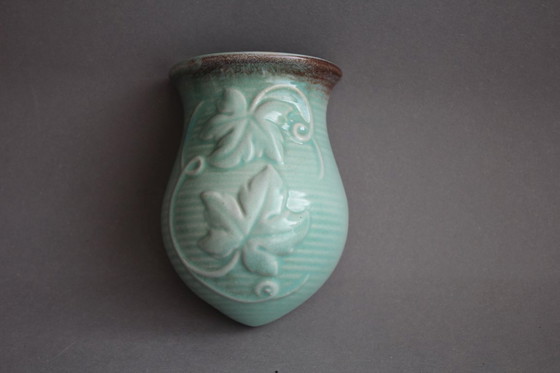 Image 1 of Lichtgroene vintage keramische wandvaas met wijnrankdecoratie.