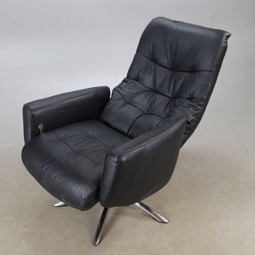 Modernist black leather armchair with a chrome X-frame base in a contemporary style, in good condition with minor signs of aging
