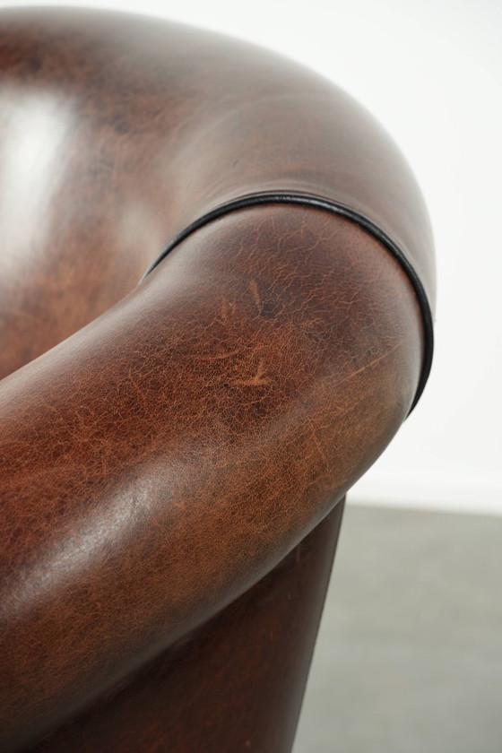 Image 1 of Mooie en karaktervolle schapenleren clubfauteuil met mooie diepe warme kleuren, zwarte biezen en een comfortabele zit