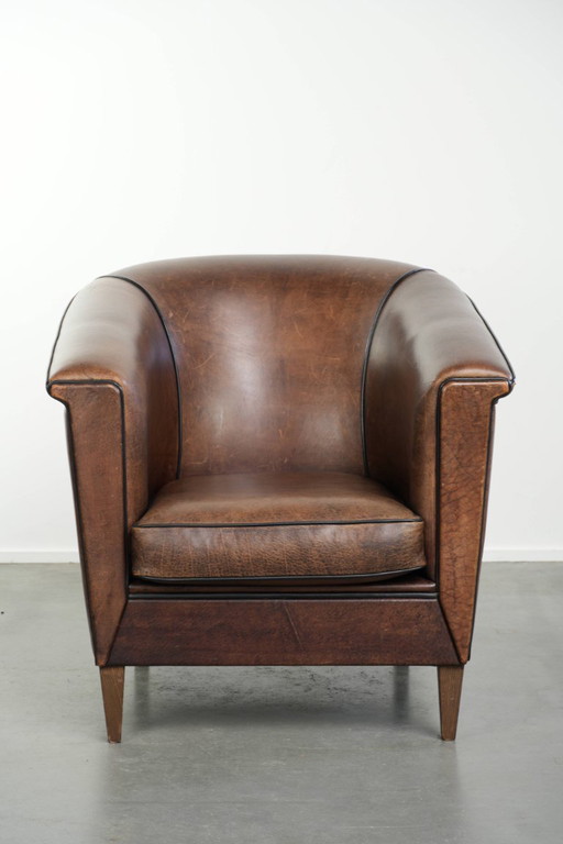 Elegante e raffinata poltrona club in pelle di pecora dal design Art Déco con profili neri.