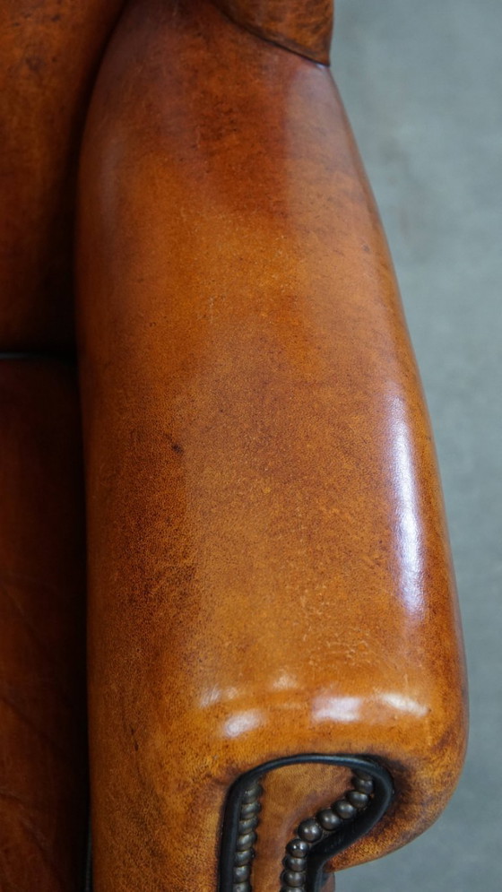 Image 1 of Comfortabele schapenleren oorfauteuil met een prachtige warme kleurstelling en een afwerking met stiksels en zwarte biezen
