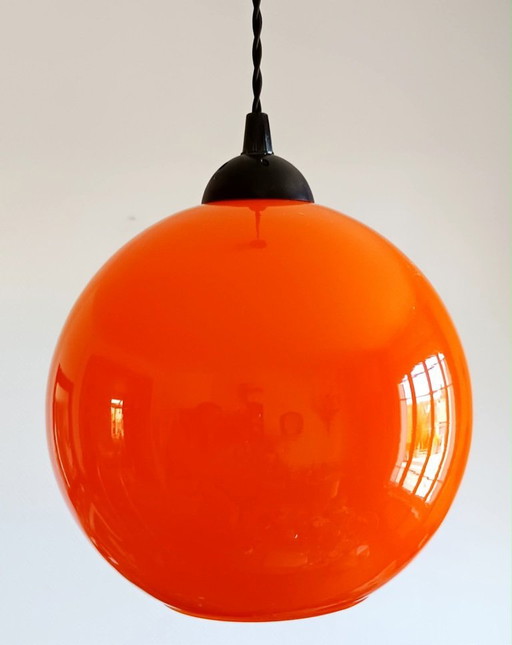 Vintage oranje hanglamp in de vorm van een bol uit het ruimtetijdperk.