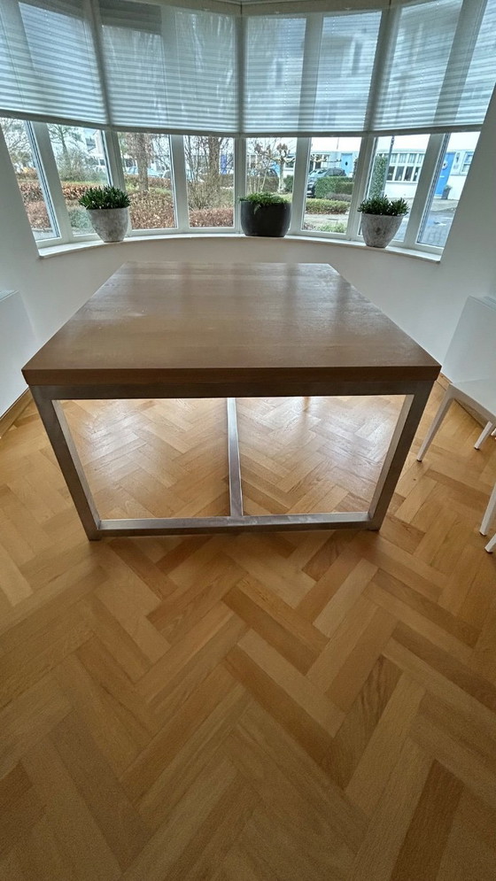 Image 1 of Mesa de comedor de diseño con estructura de acero inoxidable y marco de roble blanqueado.