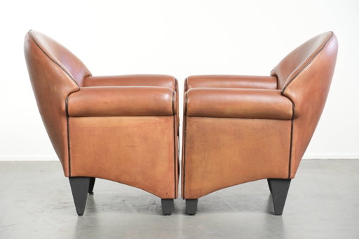 2 poltrone di design Bart van Bekhoven in pelle di pecora con schienale arrotondato e profili neri.