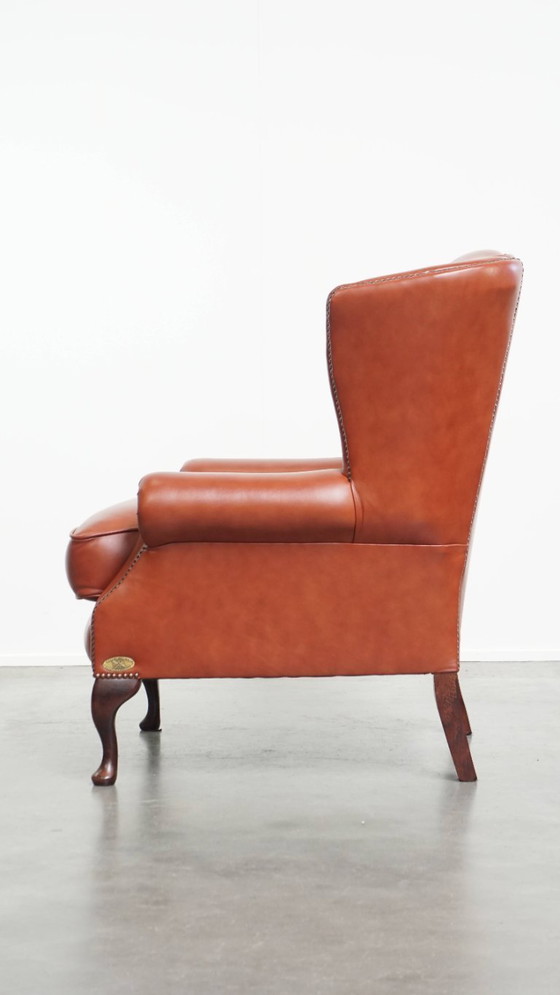 Image 1 of Elegante en comfortabele gladde Engelse rundleren chesterfield oorfauteuil met sierlijke pootjes