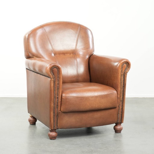 Fauteuil en bon état, en peau de mouton avec une finition raffinée et des clous décoratifs.