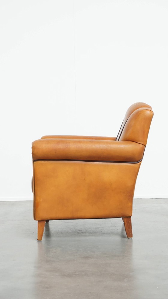 Image 1 of Schapenleren armchair met een afwerking met donkerbruine biezen