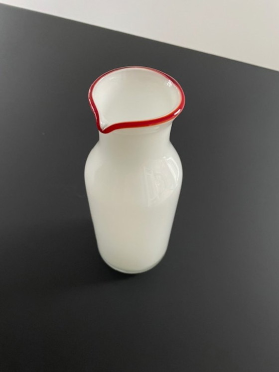 Image 1 of Caraffa dal design scandinavo in vetro bianco con bordo rosso.