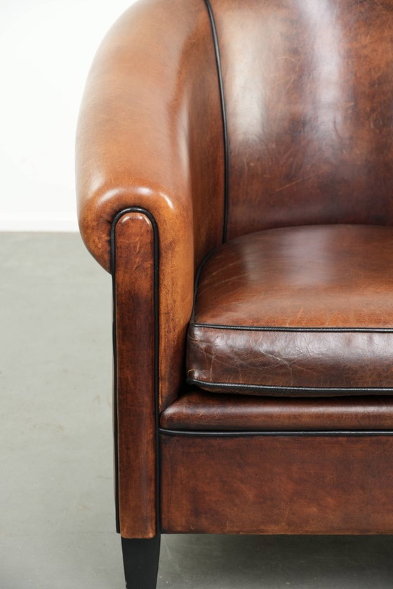 Image 1 of Mooie en karaktervolle schapenleren clubfauteuil met mooie diepe warme kleuren, zwarte biezen en een comfortabele zit