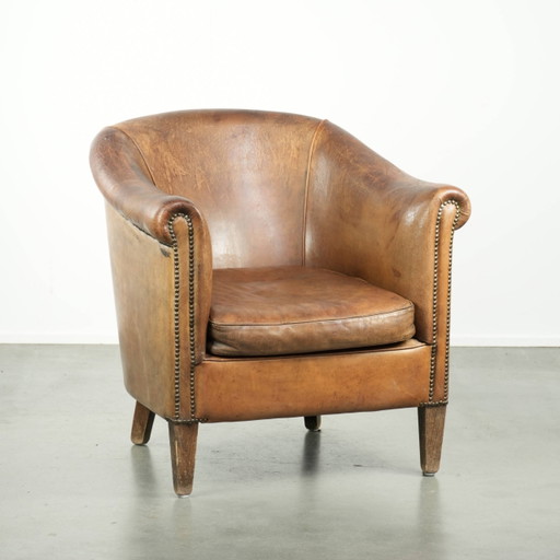 Fauteuil club vintage en cuir de mouton, orné de clous décoratifs et d'un look élégant