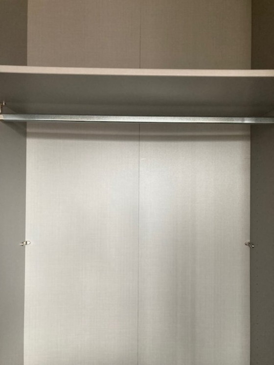 Image 1 of Hoher, dunkelgrauer zweitüriger Kleiderschrank mit vertikalen silbernen Griffen.