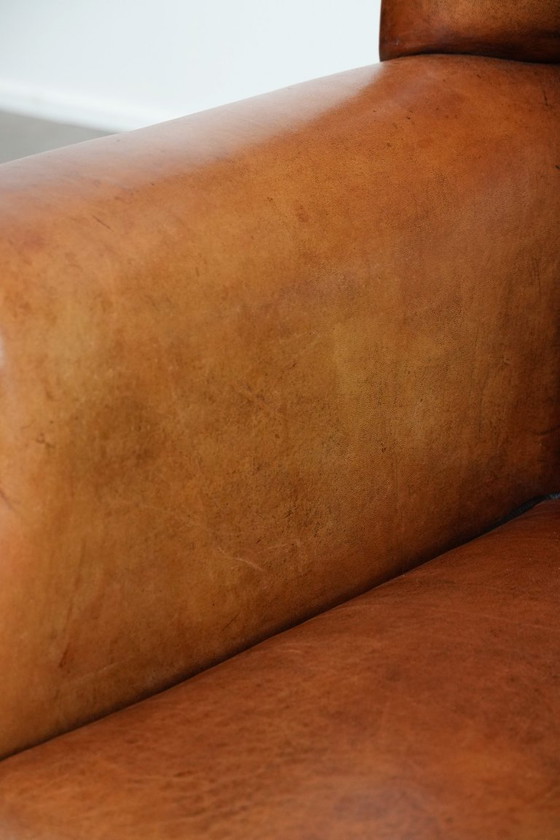 Image 1 of Grote schapenleren oorfauteuil met zwarte biezen en siernagels