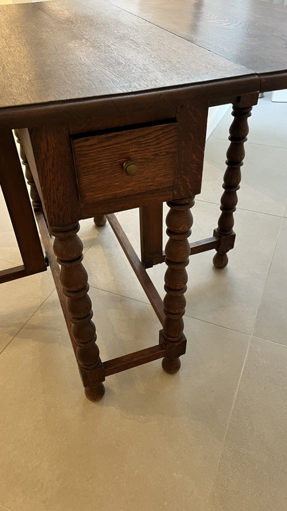 Image 1 of Mesa plegable de roble macizo estilo neojacobino inglés con patas abatibles.
Circa 1925–1940