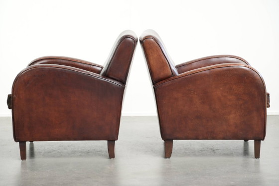 Image 1 of 2x dunkel cognacfarbene Schaffellsessel mit abgerundeten Formen und elegantem Design