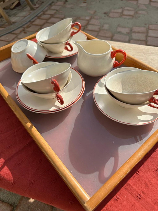 Set van 7 aardewerken kopjes, 5 schotels en 1 melkkan. Gemerkt met afbeelding van een springend hert en het woord 'Holland'.    