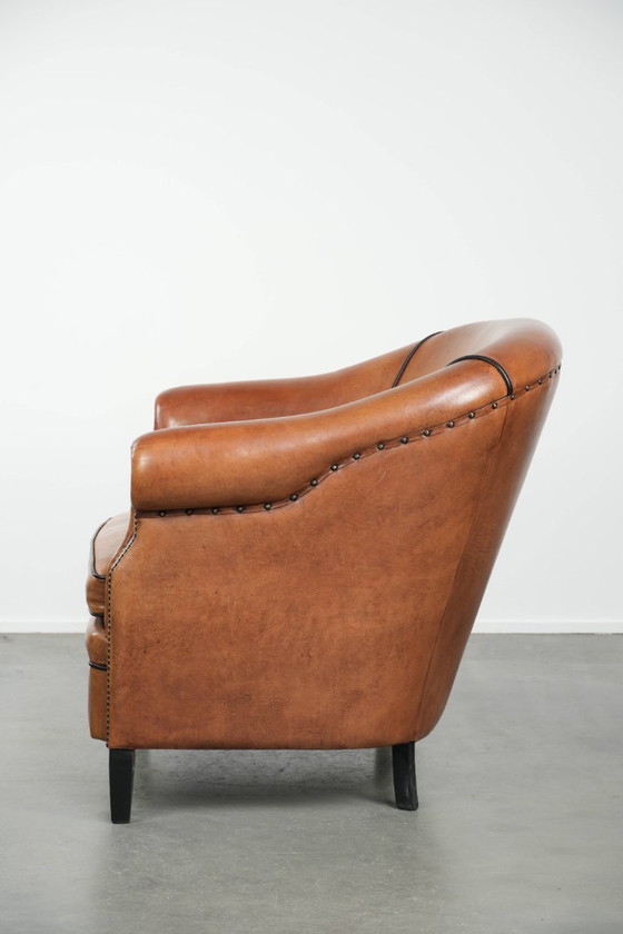 Image 1 of Amplio sillón club de estilo inglés, tapizado en piel de oveja, con acabado de clavos decorativos y ribetes negros.