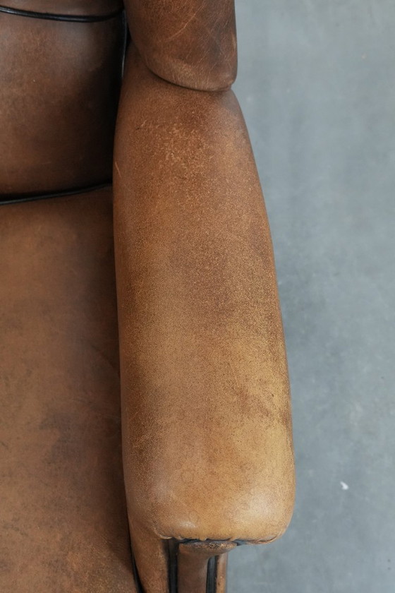 Image 1 of Poltrona a orecchioni in pelle di pecora con profili neri, in buone condizioni.