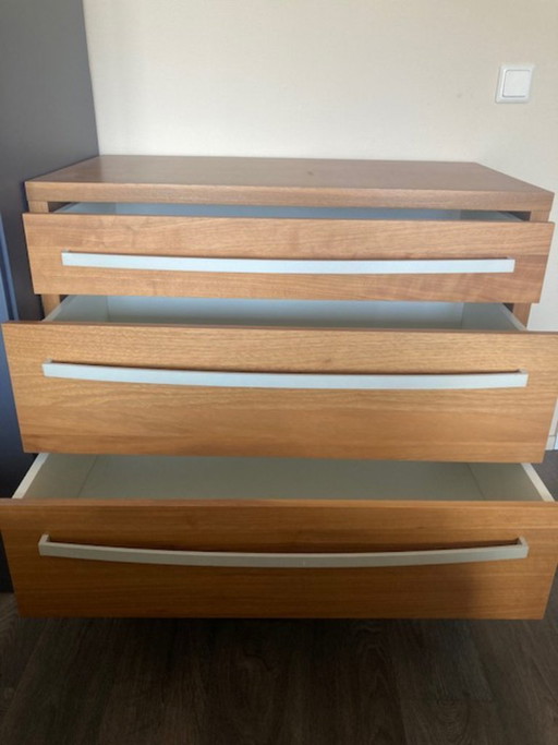Cómoda vintage IKEA MALM con tres cajones, acabado en chapa de madera, tiradores y patas de color plateado.