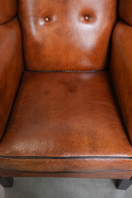 Image 1 of Grote oorfauteuil gemaakt van schapenleer met zwarte biezen en siernagels