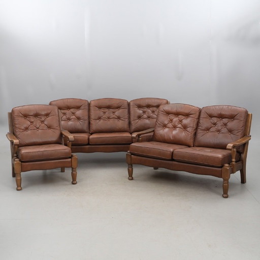 A vintage brown three-piece sofa set in leather with wooden armrests and turned legs, comprising a 1-seater, 2-seater and 3-seat