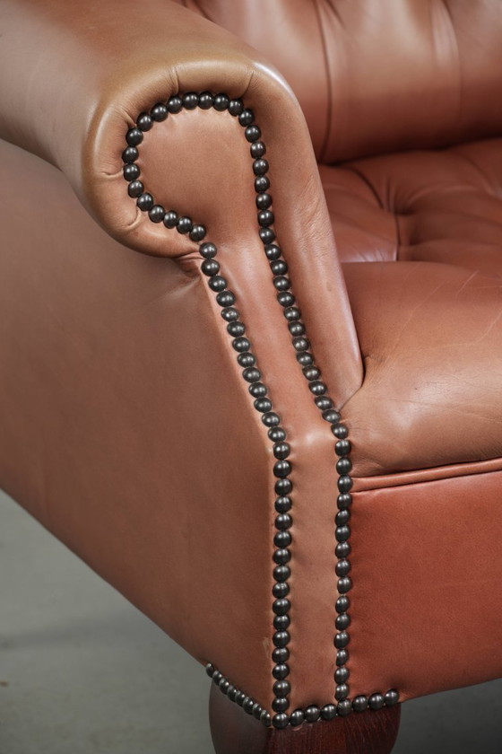 Image 1 of Fauteuil Chesterfield à oreilles en cuir de vachette anglais, assise capitonnée, avec une belle patine et de jolies couleurs.