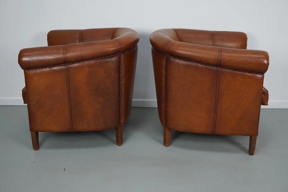 Image 1 of Dit paar cognackleurige leren clubfauteuils komt uit Nederland. Ze zijn bekleed met cognackleurig leer en zijn voorzien van meta