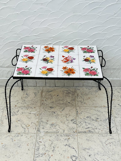 Vintage salontafel van smeedijzer met bloemmotief op de tegels.