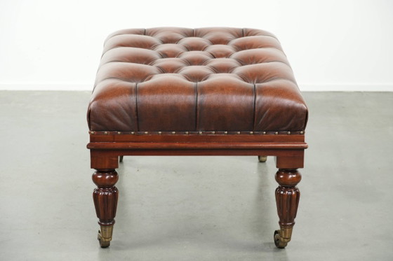 Image 1 of Grote bruine rundleren chesterfield hocker in Engelse stijl met sierlijke poten en messing wieltjes