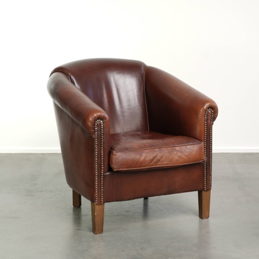 Characterful sheepskin club armchair in a dark cognac color in English style