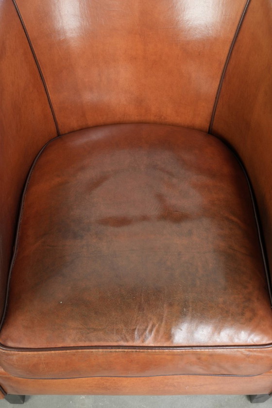 Image 1 of Vintage schapenleren clubfauteuil met een warme kleurstelling en afgewerkt met zwarte biezen