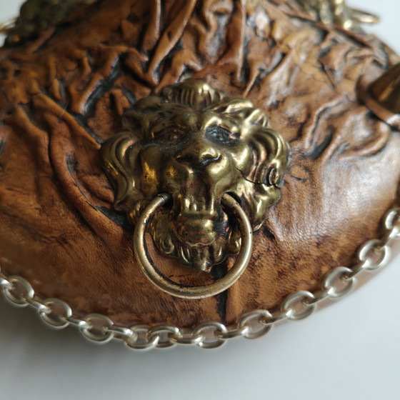 Image 1 of Carafe vintage recouverte de cuir, ornée de têtes de lion et d'une chaînette