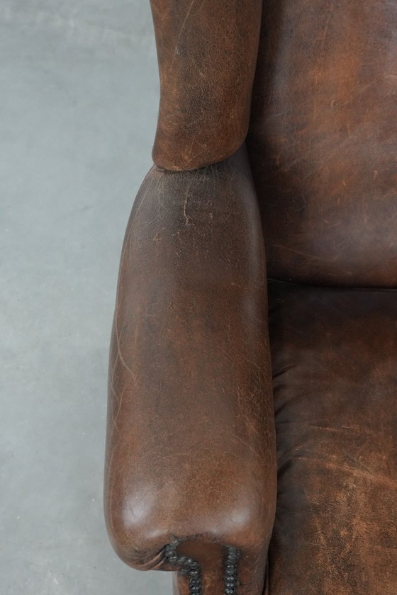 Image 1 of Caratteristica poltrona vintage di grandi dimensioni con ali laterali, realizzata in pelle di pecora.