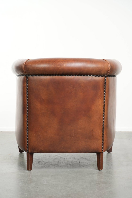Image 1 of Poltrona club in montone color cognac caldo, rifinita con borchie decorative.