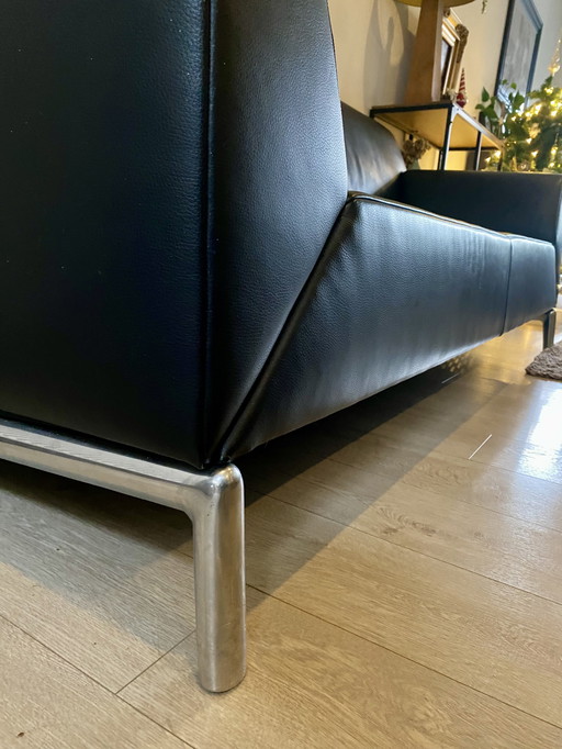 Sofá de diseño en piel negra con reposabrazos regulables.