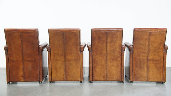 Image 1 of 4 x Vintage schapenleren eetkamerstoel met zwarte biezen op wieltjes