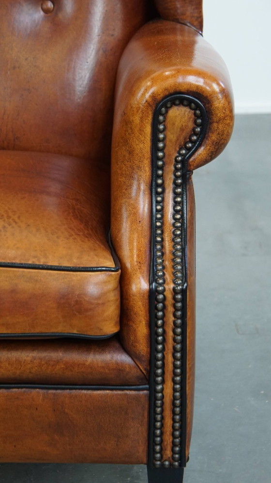 Image 1 of Comfortabele schapenleren oorfauteuil met een prachtige warme kleurstelling en een afwerking met stiksels en zwarte biezen