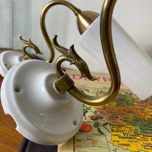Pair of brass gooseneck wall lights with white glass and porcelain mounting rosettes